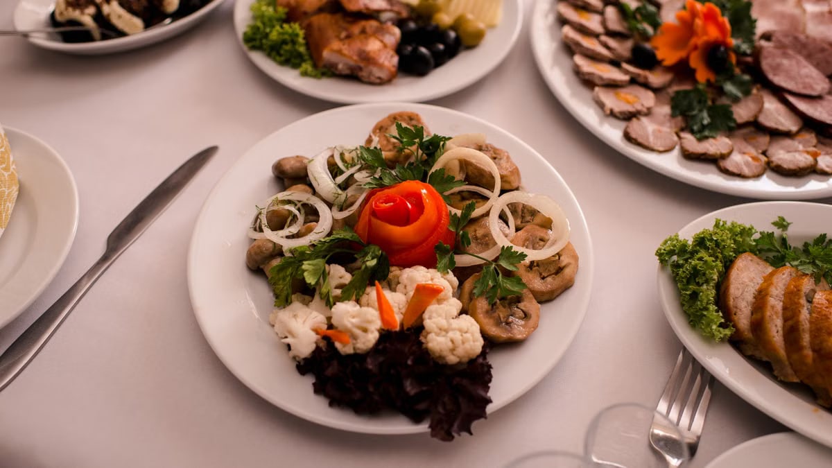 Beautifully arranged gourmet plates with meats, cheeses, and garnishes on a white table setting.